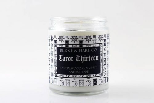 Burke Hare Co. Tarot Thirteen candle. A white candle in a clear jar with a label patterned with skulls.