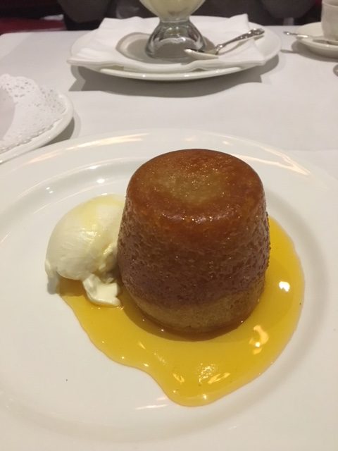 The golden syrup sponge from Rules, in London. I think about this dessert a lot. A gold sponge cylinder on a plate with a gold yellow syrup around it on the plate 