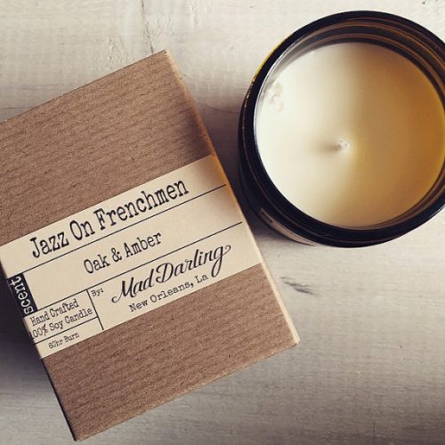 Mad Darling Jazz on Frenchmen candle. A cardboard box with printed text. Next to it is a white candle in an amber jar.