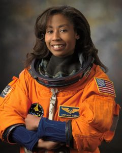 Wikimedia picture of Stephanie Wilson in her flight suit wearing patches