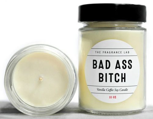 An off-white candle in a clear jar with a black lid. The label is white with thin, black block letters that read Bad Ass Bitch.