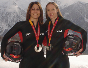 Valerie and Shauna stand next to each other wearing their olympic medals.