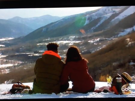 Wills and Becca sit on a mountain top with a staw hat next to them