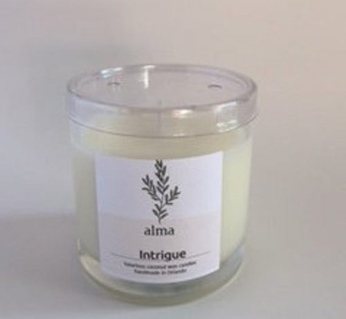 A white candle in a clear jar in front of a white background. The label has a leafy branch on it.
