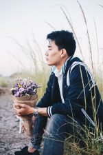 Portrait of young asian handsome man in meadow with dry flower