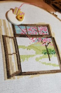 Mostly done outside of a Spring pattern of a wood framed window looking out onto a light green lawn with a tree featuring pink blossoms in the background