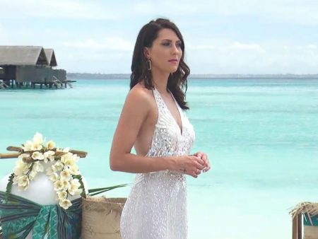 Becca wears a white gown and looks out into the sea