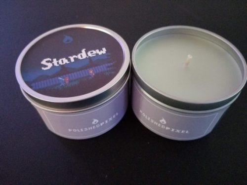 A white candle in a metal tin. The label is purple with a pixelated 8-bit character.