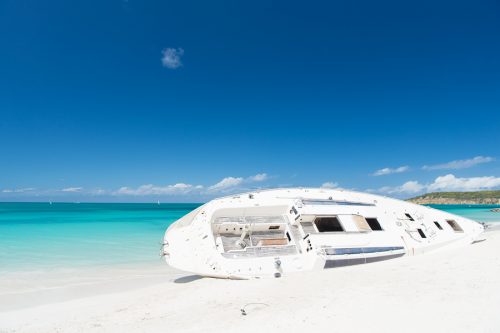 Ship or luxury white boat lay on sand beach, skyline background. After storm always return sun. Yacht on st.johns beach. Entertainment summer vacation yachting. Boat yacht landed on sand coast.