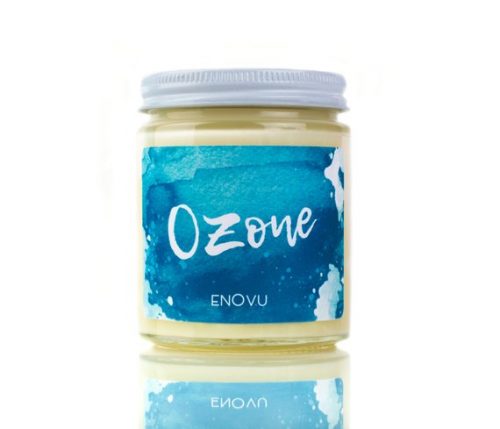 A white candle in a glass jar and white metal lid. The label has an ombre blue watercolor print on it.
