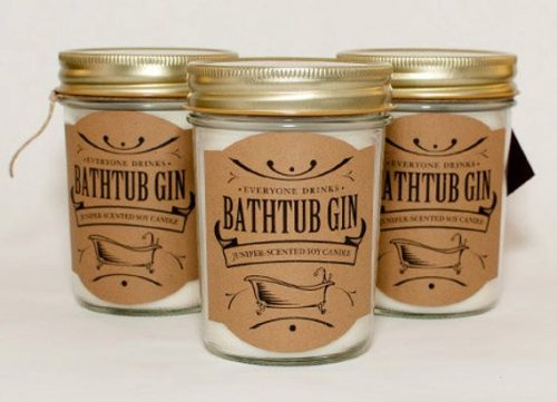A white candle in a glass mason jar. The label is butcher paper with a bathtub on it.