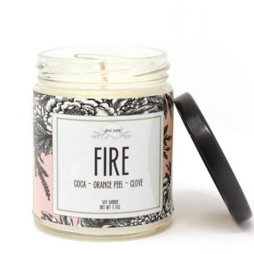 A white candle in a glass jar with a black metal lid. The label is light pink with grey flowers. 