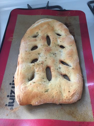 A leaf shaped loaf of bread with green herbs