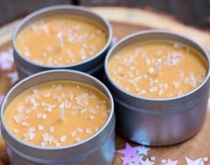 A trio of caramel colored candles in short metal tins.