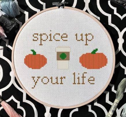A cross stitch that says Spice Up Your Life with two pumpkins and a latte in the middle 