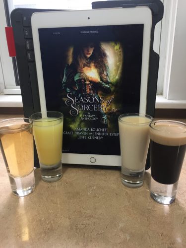Four shot glasses arranged around an ipad with a copy of Seasons of Sorcery