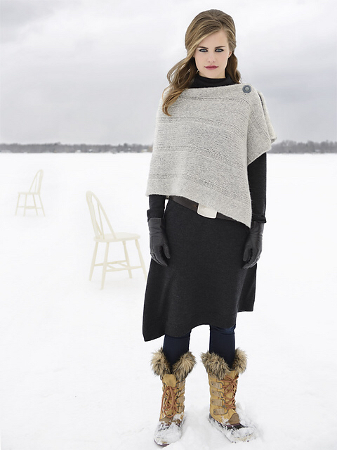 Image from Sarah Smolund of a woman in a long blue dress in the snow wearing the wrap sweater. This one is grey and it buttons across the shoulders and hangs down front and back