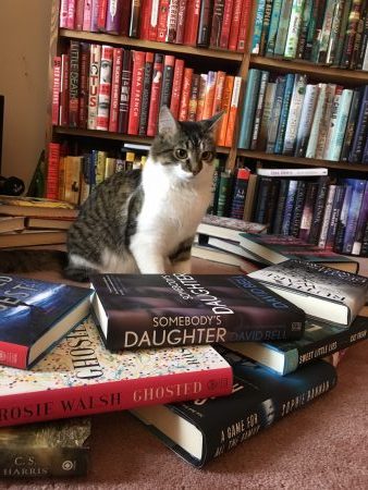 Fisher is sitting in the middle of a ring of books looking deeply confused