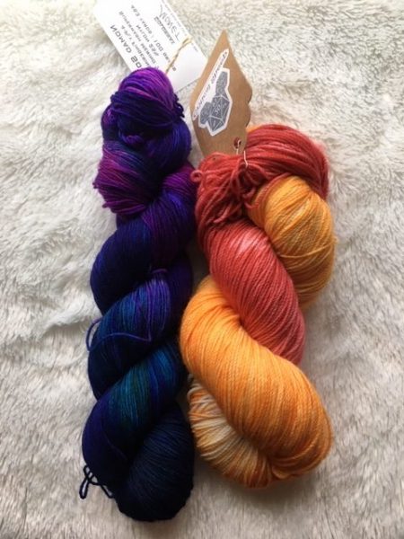 Two skeins of yarn side by side against white background. The first skein is purple and an intense blue with just a little teal mixed in. The second skein a peachy-orange with red mixed in.