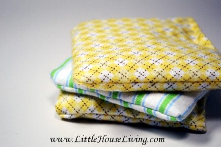 Three handwarmers stacked on each other. Two have a yellow check pattern and one is blue and white striped.