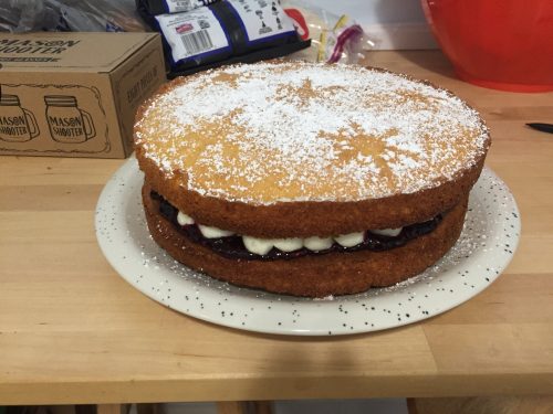 Two layers of sponge cake with piped buttercream and blackberry jam between.