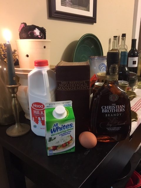 Ingredients! Milk, egg whites in a carton, an actual egg, and brandy, all displayed with my beloved Mrs Beeton