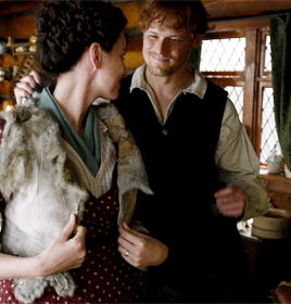 Jamie putting a shawl on Claire's shoulders, over this very cute rabbit fur vest.