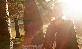 Brianna, approaching the stone with the sun flaring behind her.