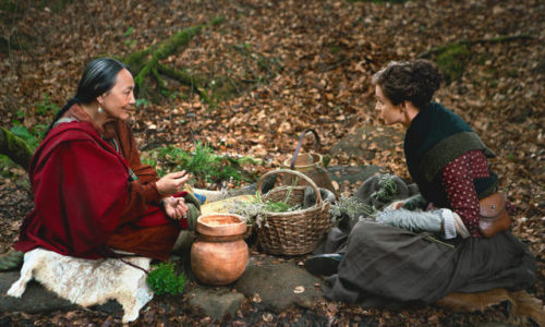 Claire sitting with Adawehi with baskets and plants between them.