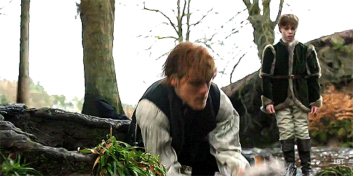 Jamie pulling a fish out of the water while Willie looks on.