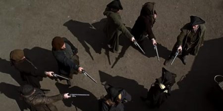 A shot from above of a semi circle of men holding the guards at gunpoint.
