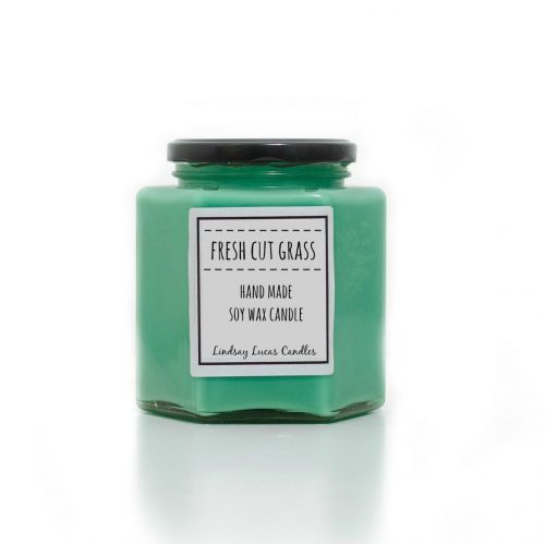 A vibrant green candle in a hexagonal glass jar.