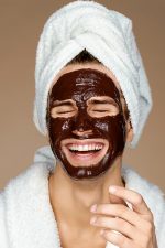 Laughing man with chocolate facial mask.