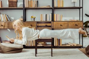 adult woman in glasses laying on chair and reading book