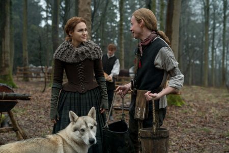 Ian hauls water for Bree while Rollo looks on. Jamie is working in the back drop.