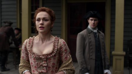 Bree looks nervously down the street into Wilmington while Lord John waits behind her.