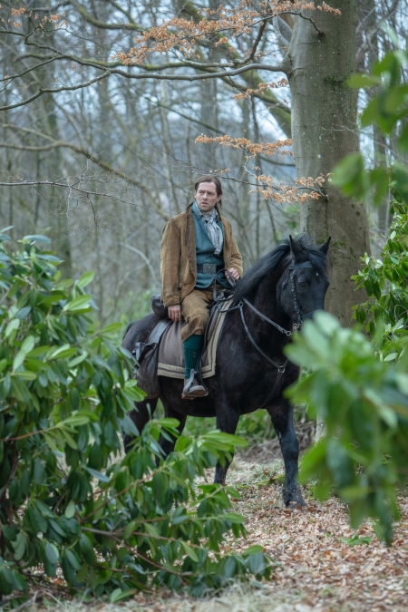 Roger on horseback riding through the woods