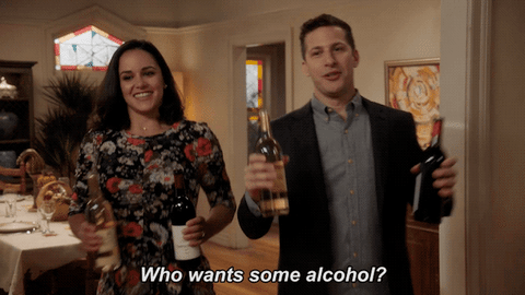 Amy and Jake from Brooklyn 99 hold up bottles of wine and ask Who wants some alcohol?