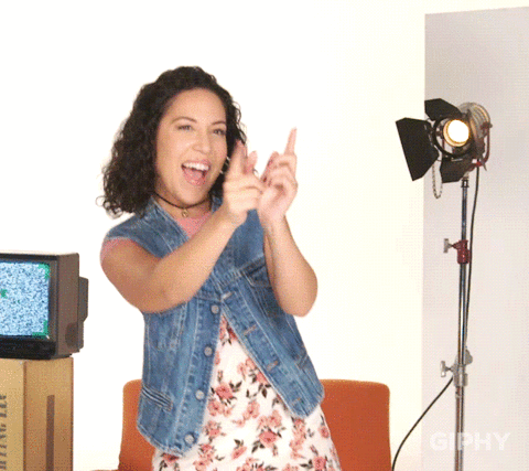 A woman happily dancing and doing finger guns.