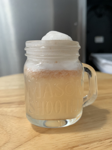 A light pink drink in a mason jar with foam on top.