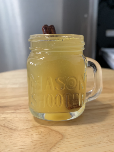 A light orange warm cocktail with a cinnamon stick