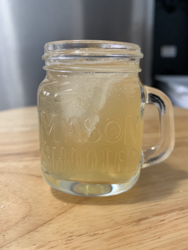 A pale yellow fizzy cocktail in a mason jar