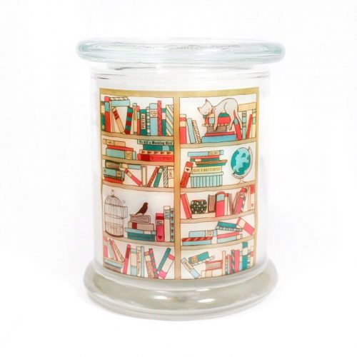 A large glass candle jar with a glass lid. The jar has an illustration of a bookshelf with books and a sleepy cat.