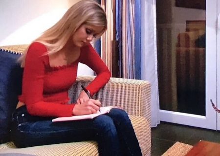 Hannah G sits on a sofa and writes in her journal