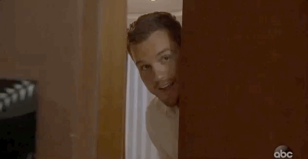 Colton closes the hotel room door while throwing up a peace sign