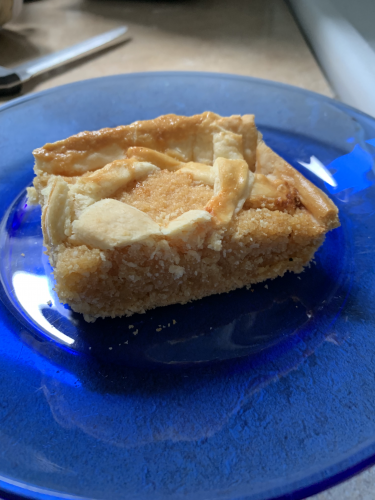 A square cut piece of treacle tart on a glass plate.