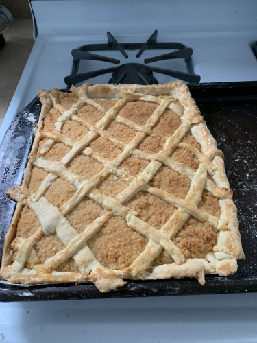 A misshapen treacle tart with wonky lattice work on a baking sheet.
