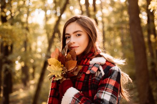 Cheerful beautiful girl in red sweater outdoors on beautiful fall day.