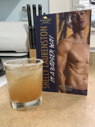 A light orange margarita next to a copy of In a Badger Way