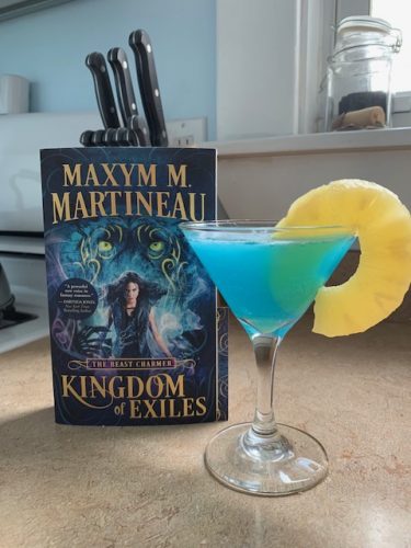 A blue slush cocktail in a martini glass with a pineapple ring